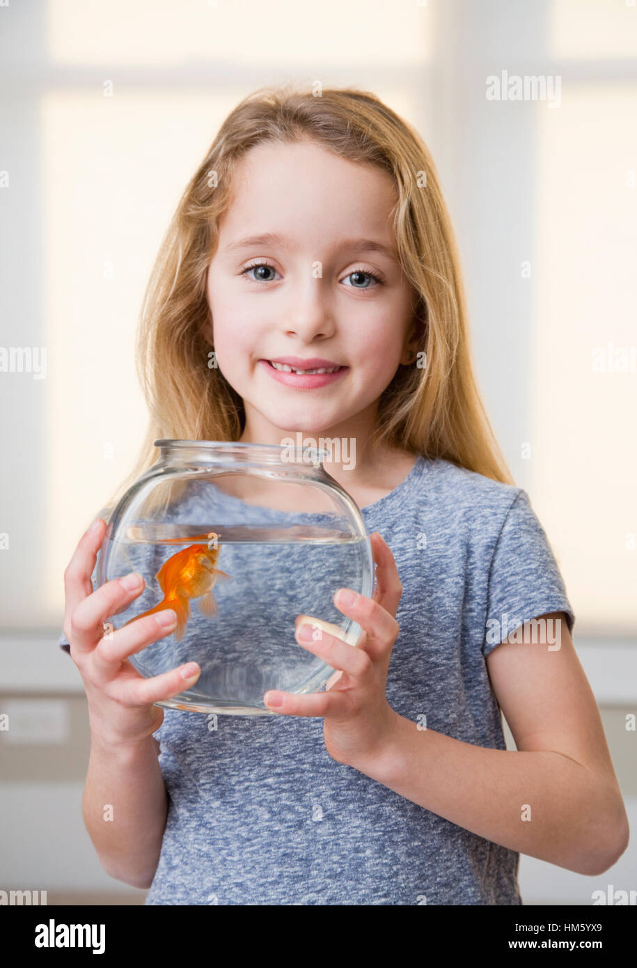 Portrait of Girl (6-7) holding goldfish in fishbowl Banque D'Images