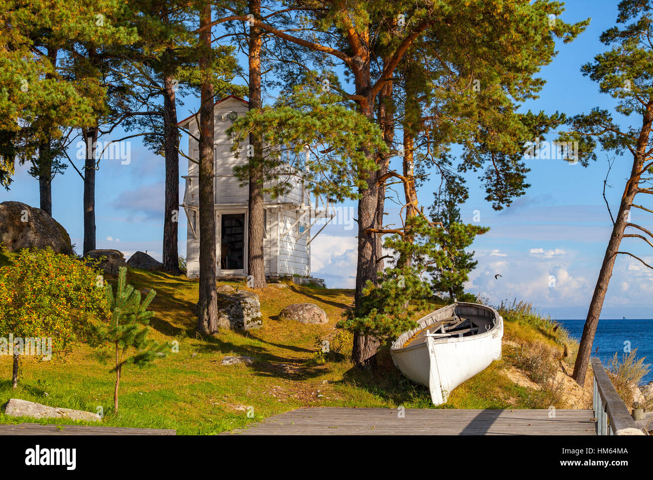 Côte rocheuse de la mer Baltique avec bateau blanc, Fisher et maison en bois de pins. Journée ensoleillée. Banque D'Images