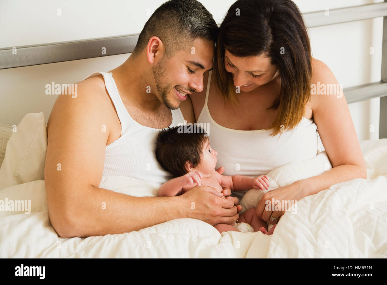 Père et mère tenant son (1 mois) au lit Banque D'Images