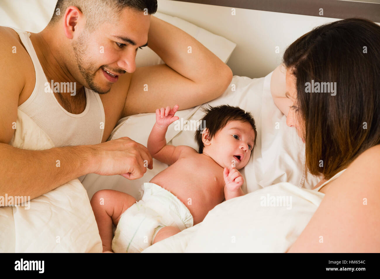 Père et mère couchée avec fils (1 mois) au lit Banque D'Images