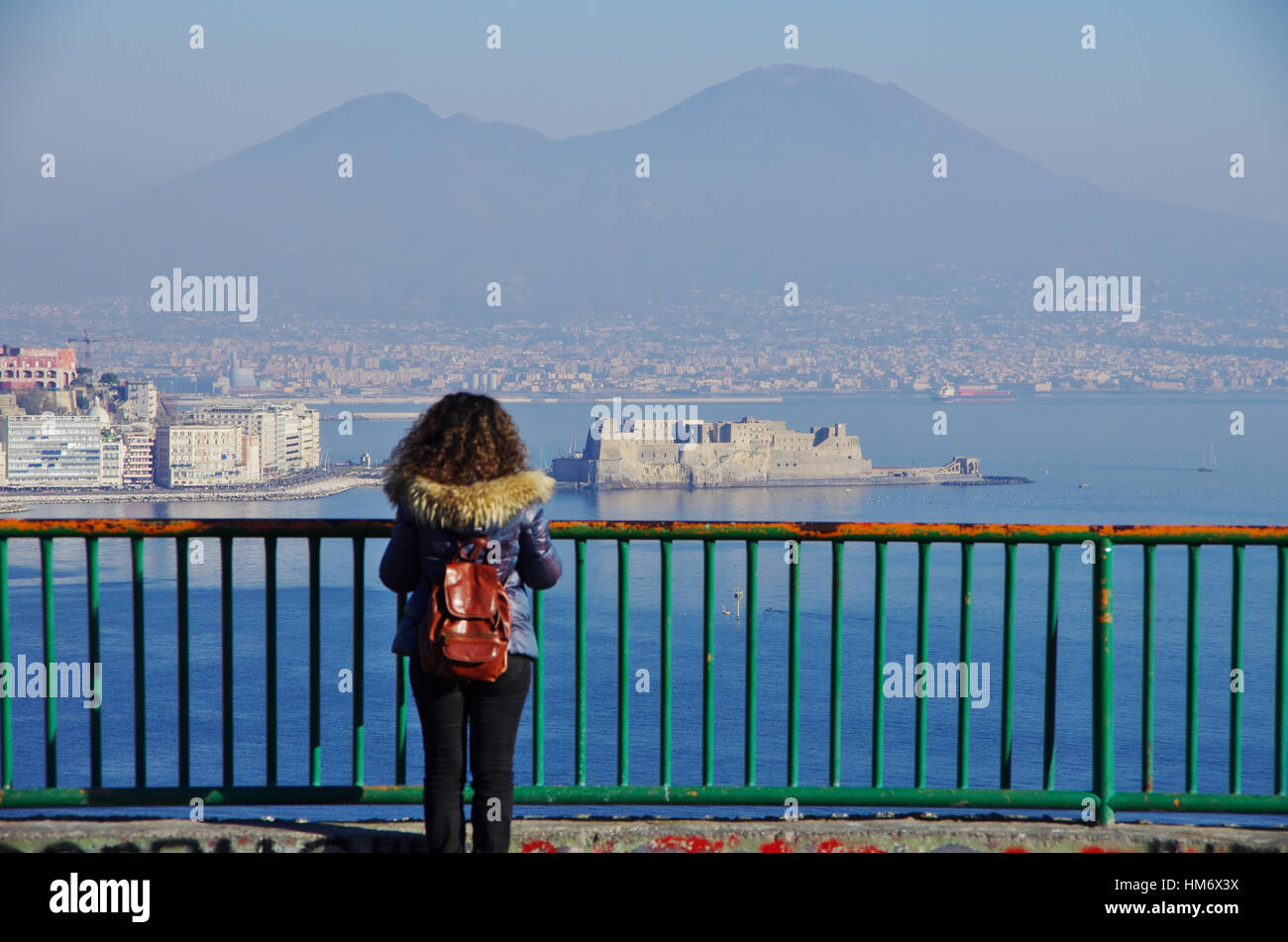 Vue aérienne de Naples et son golfe, avec le Vésuve en arrière-plan. Une jeune femme debout sur un balcon tout en regardant le paysage. Des vêtements d'hiver. Banque D'Images