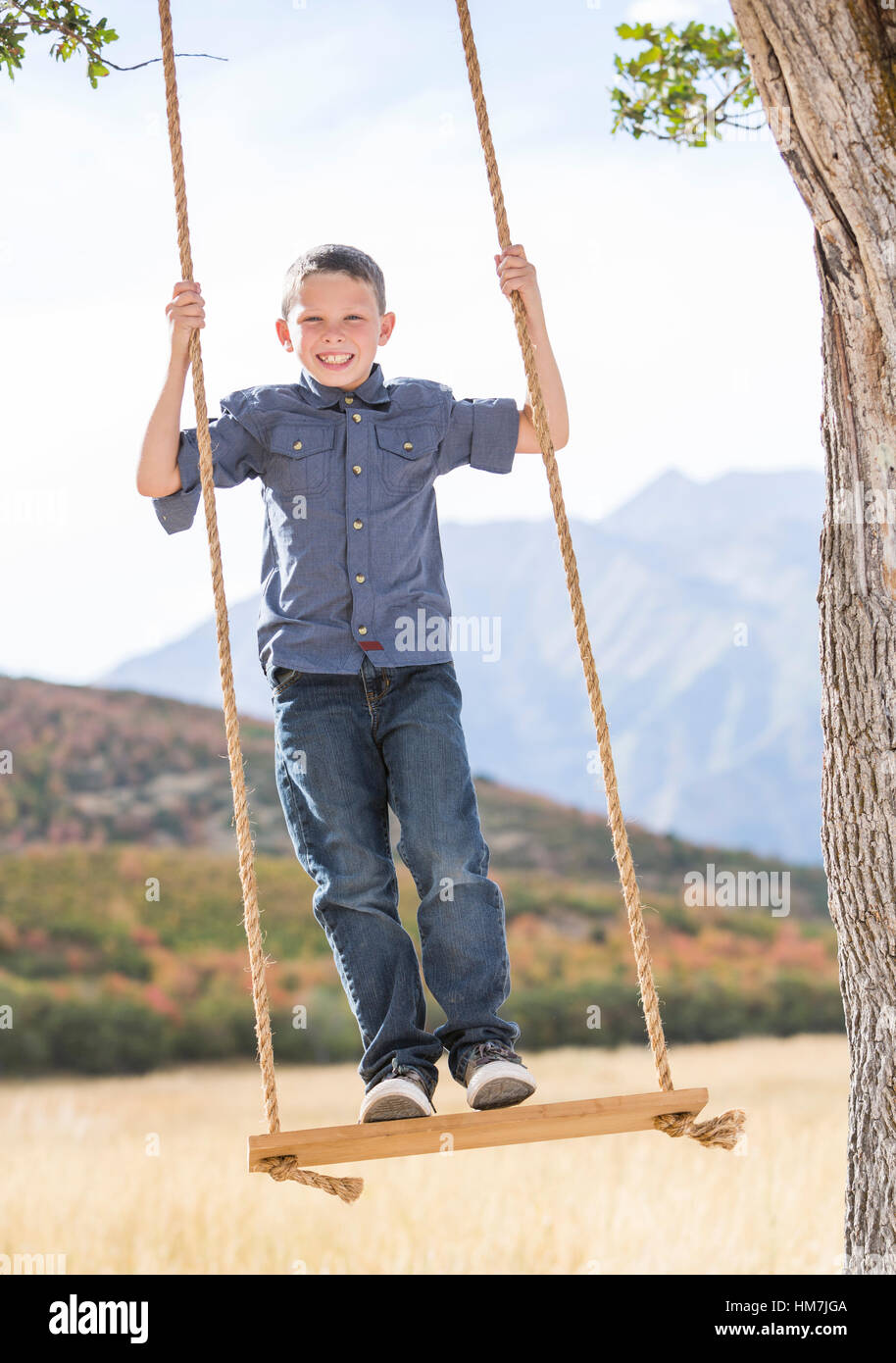 Boy (6-7) standing on swing Banque D'Images