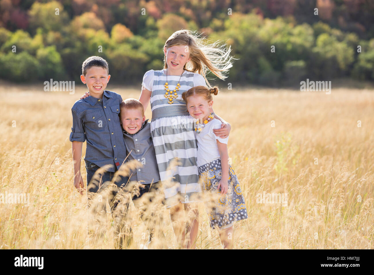 Les garçons et les filles (4-5, 6-7, 8-9) standing in field, embracing Banque D'Images