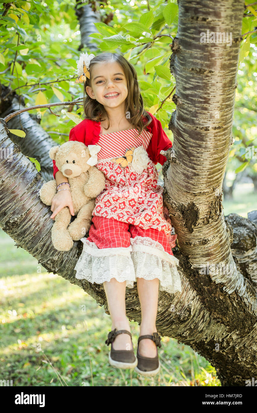 Girl with teddy bear sitting on tree Banque D'Images