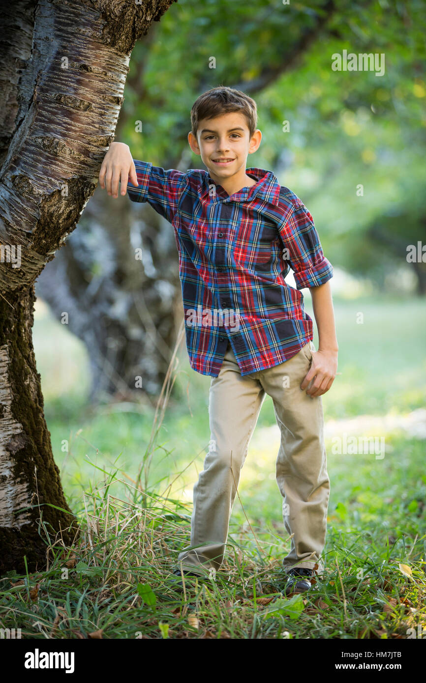 Smiling boy standing par cherry tree Banque D'Images