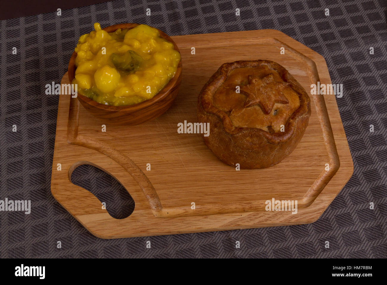 La relish Piccalilli dans un bol en bois sur une planche. Banque D'Images