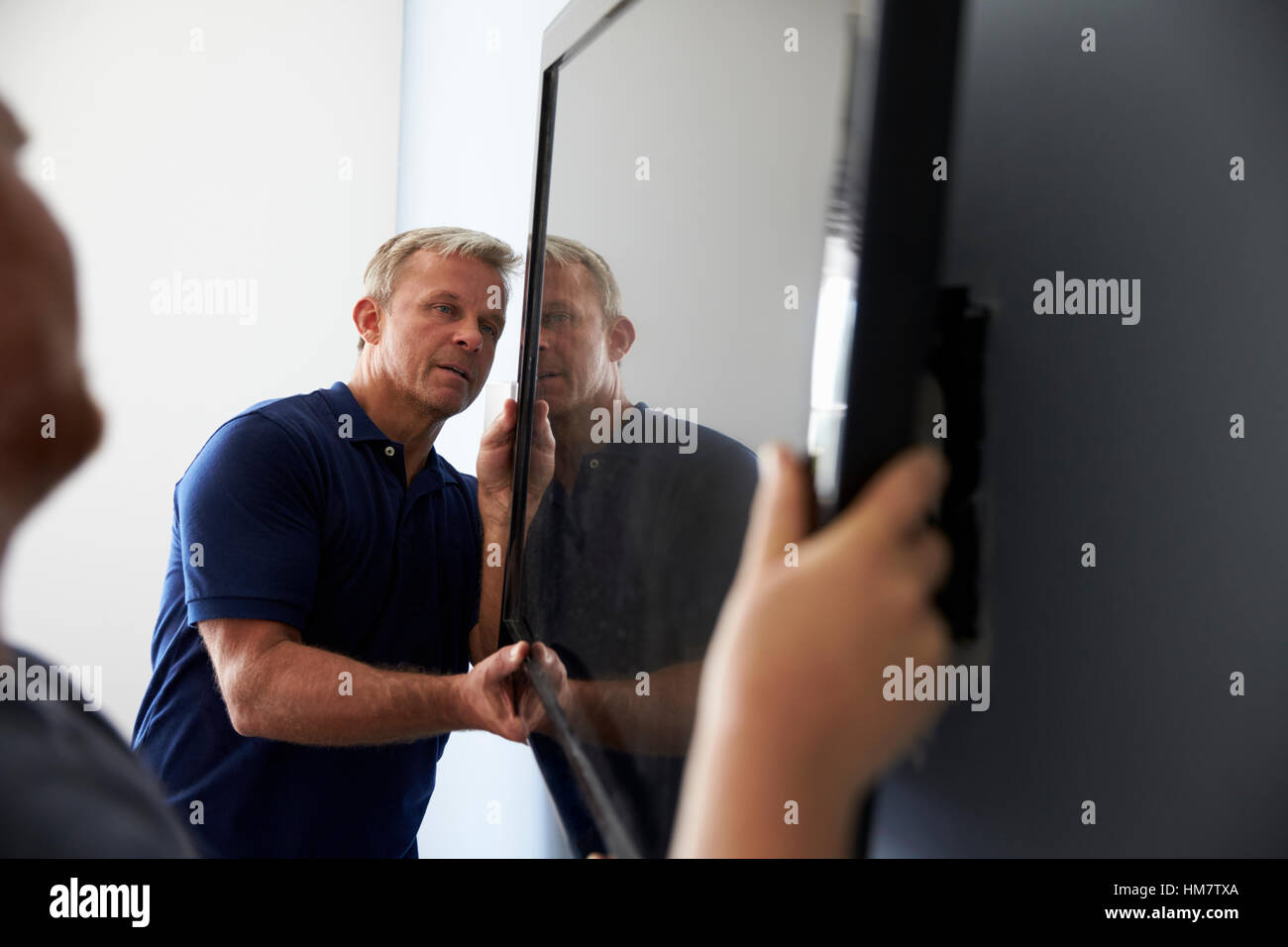 Deux hommes d'un téléviseur écran plat Montage au mur Banque D'Images