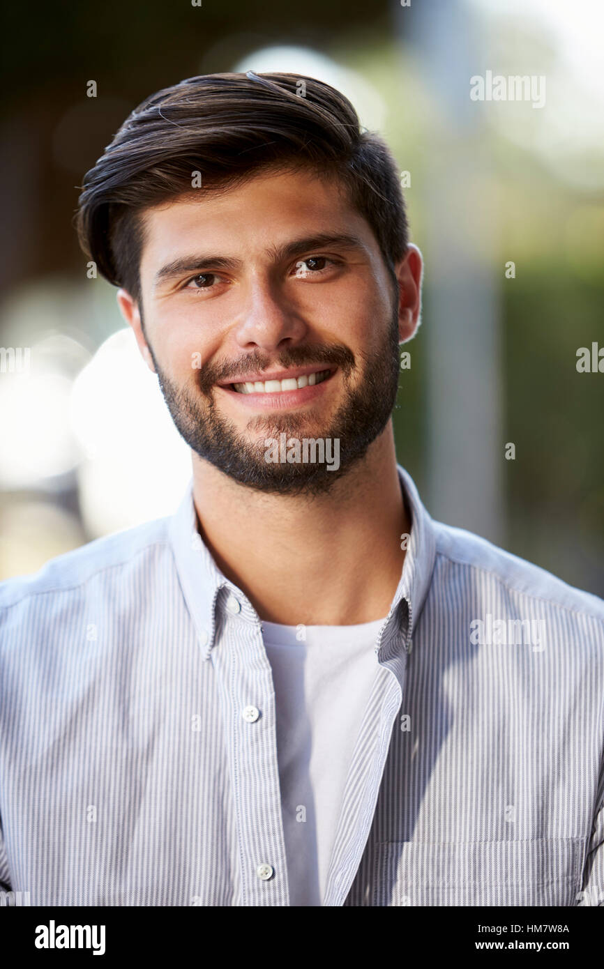 Portrait vertical de jeune homme barbu assis à l'extérieur Banque D'Images