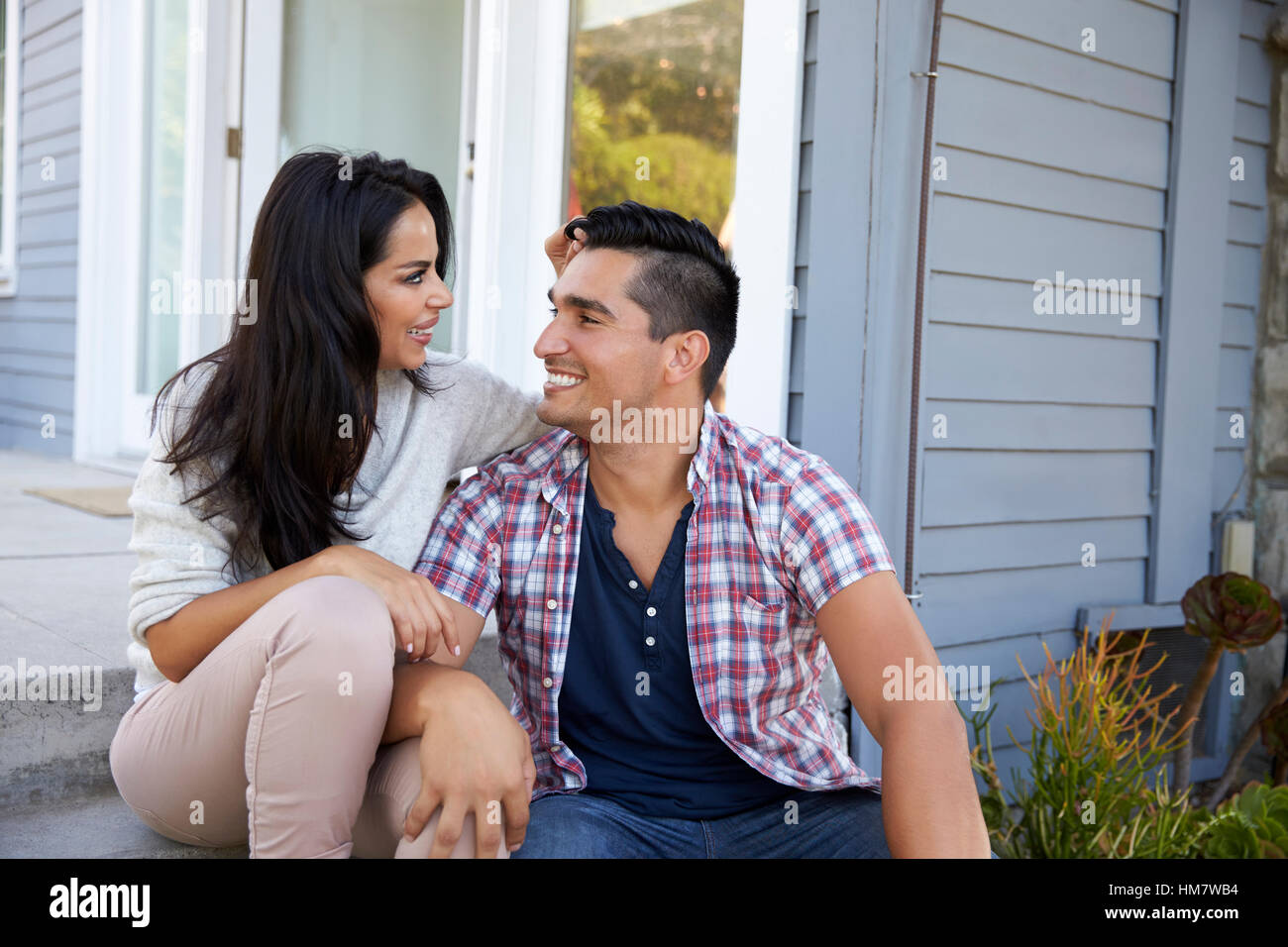 Affectionate Couple Sitting on Steps Outside Home Banque D'Images