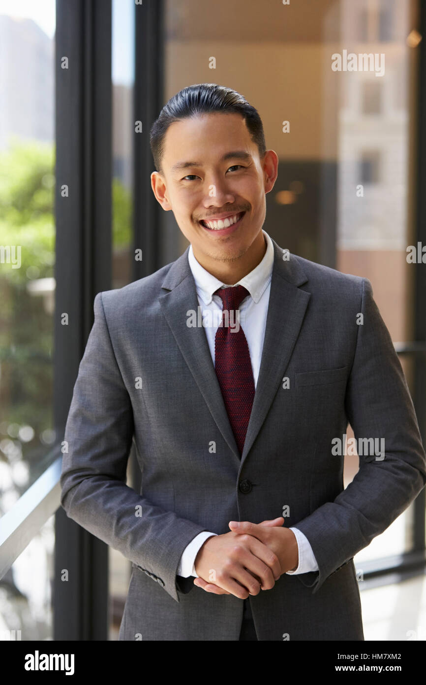 Young Asian businessman smiling to camera, vertical Banque D'Images