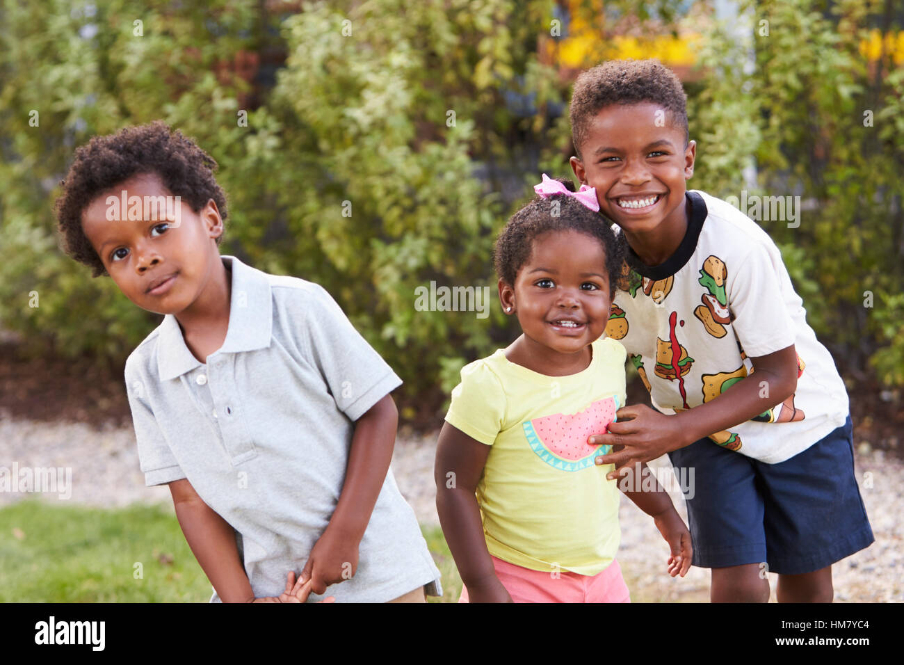 Trois enfants américains africains dans un jardin à l'appareil photo Banque D'Images