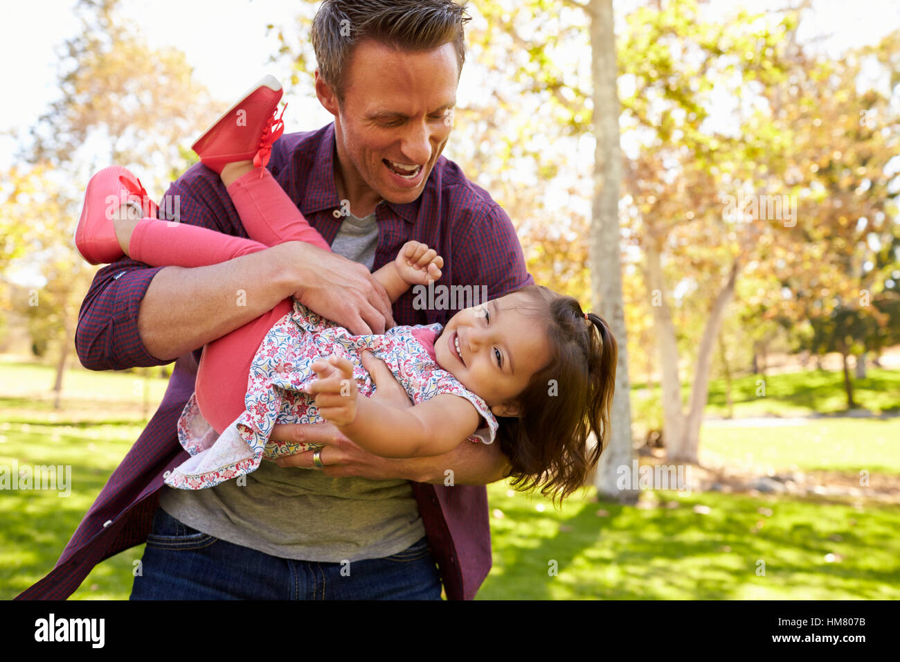 Papa, berçant dans ses bras sa fille tout-petits au parc Banque D'Images