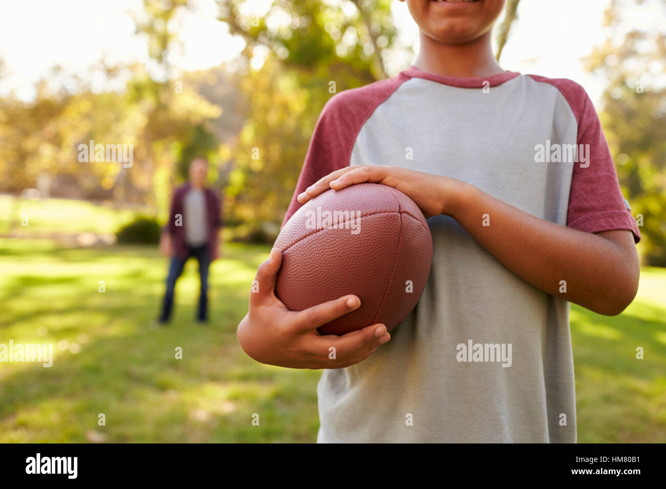 Boy holding football in park, récolte, papa en arrière-plan Banque D'Images