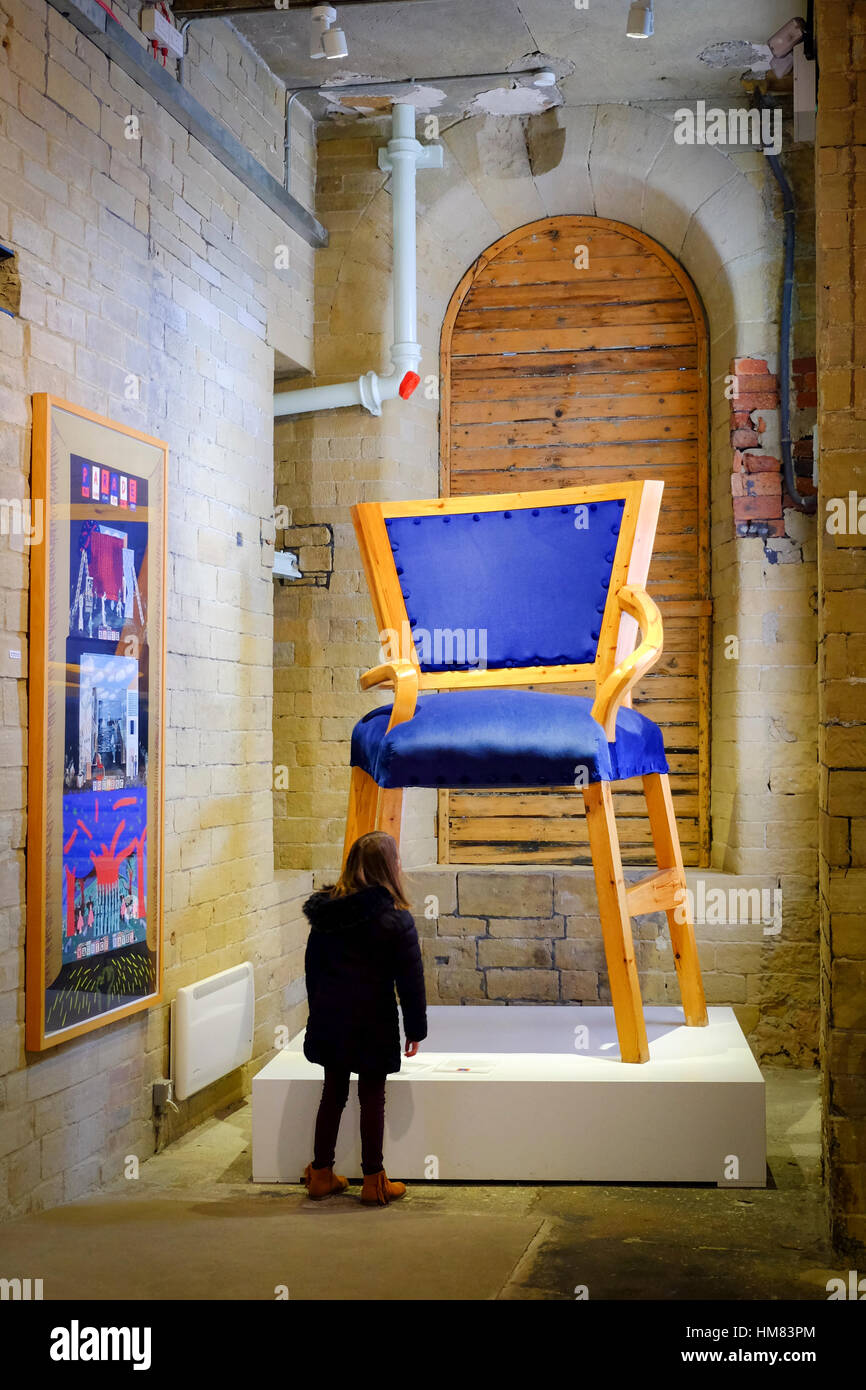 Dans l'émerveillement de l'enfant à la recherche sur à un énorme fauteuil en sels Mill, Saltaire, Bradford, West Yorkshire. Banque D'Images