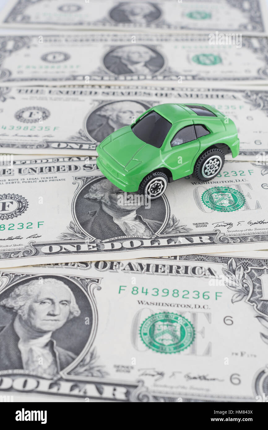 Petite voiture jouet vert sur nous 1 / 1 $ Dollar bills. Comme métaphore  pour le coût de l'automobile et de l'essence aux États-Unis, et de  carburant vert / économie verte Photo