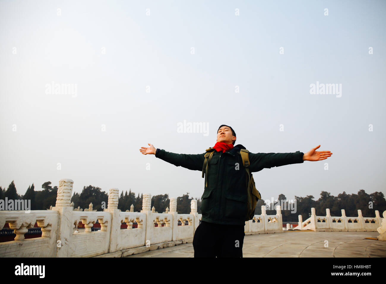 L'homme asiatique qui s'étend à bras ouverts dans l'architecture chinoise avec ciel bleu et copy space Banque D'Images