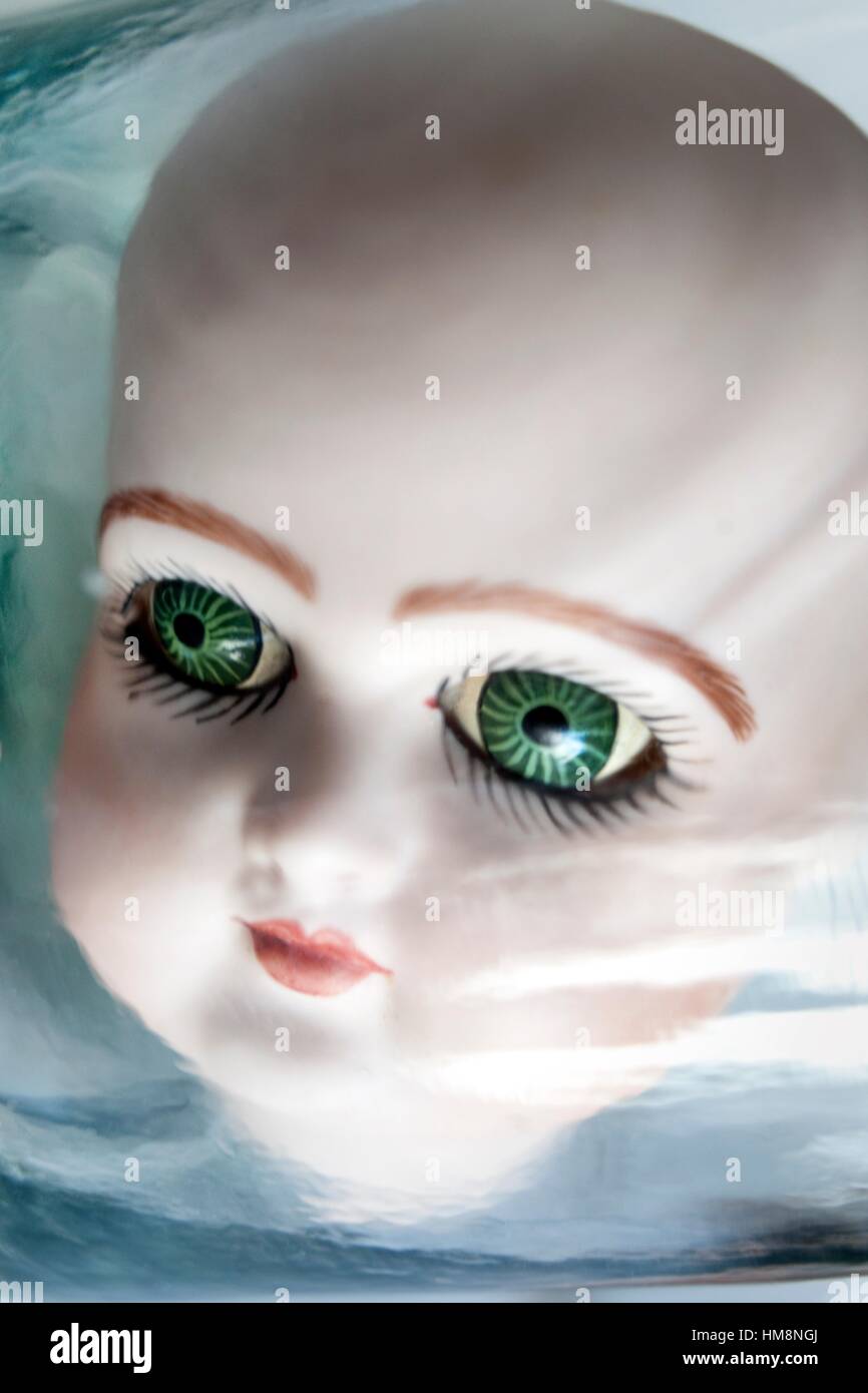 Primer Plano de una cabeza de muñeca de porcelana con ojos verdes, mirando  fijamente a la camara desde el interior de un bote de cristal. close up of  Photo Stock - Alamy