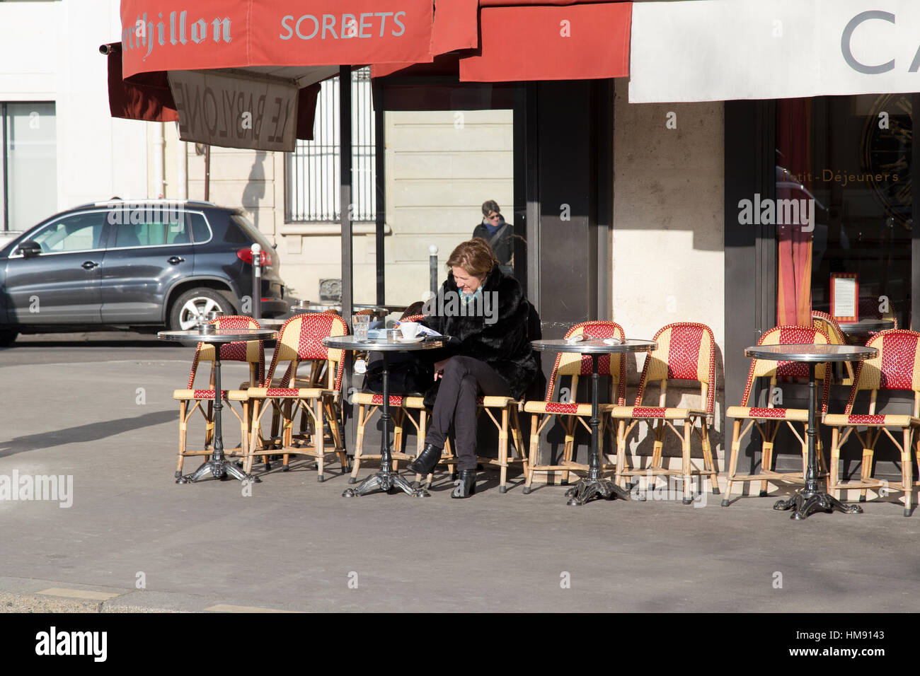 Personnes âgées femme parisien assis à l'extérieur d'un café dans le 6ème arrondissement de Paris en hiver Banque D'Images