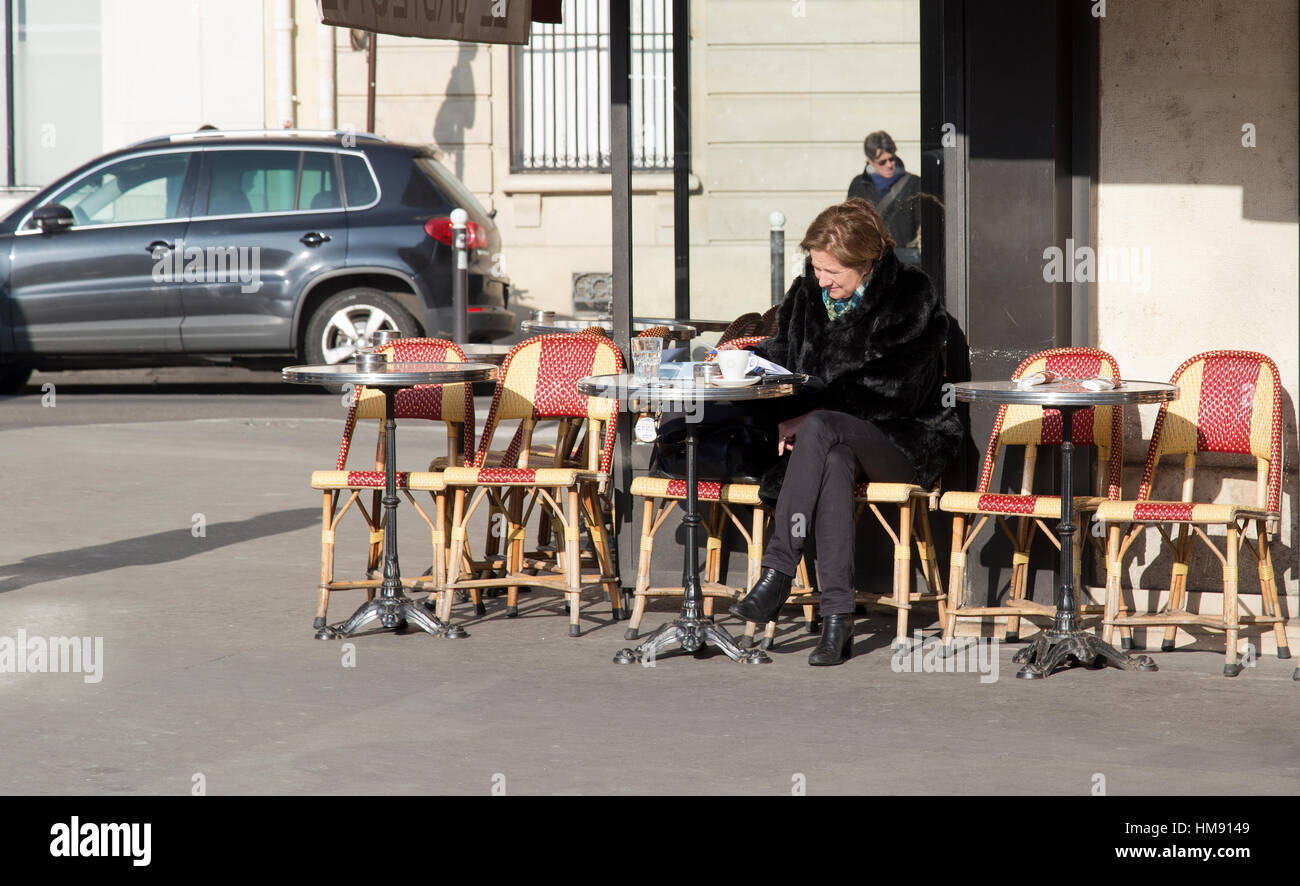 Personnes âgées femme parisien assis à l'extérieur d'un café dans le 6ème arrondissement de Paris en hiver Banque D'Images