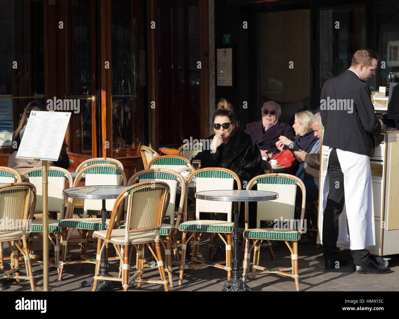 Femme assise à l'extérieur d'un café à Paris en hiver Banque D'Images