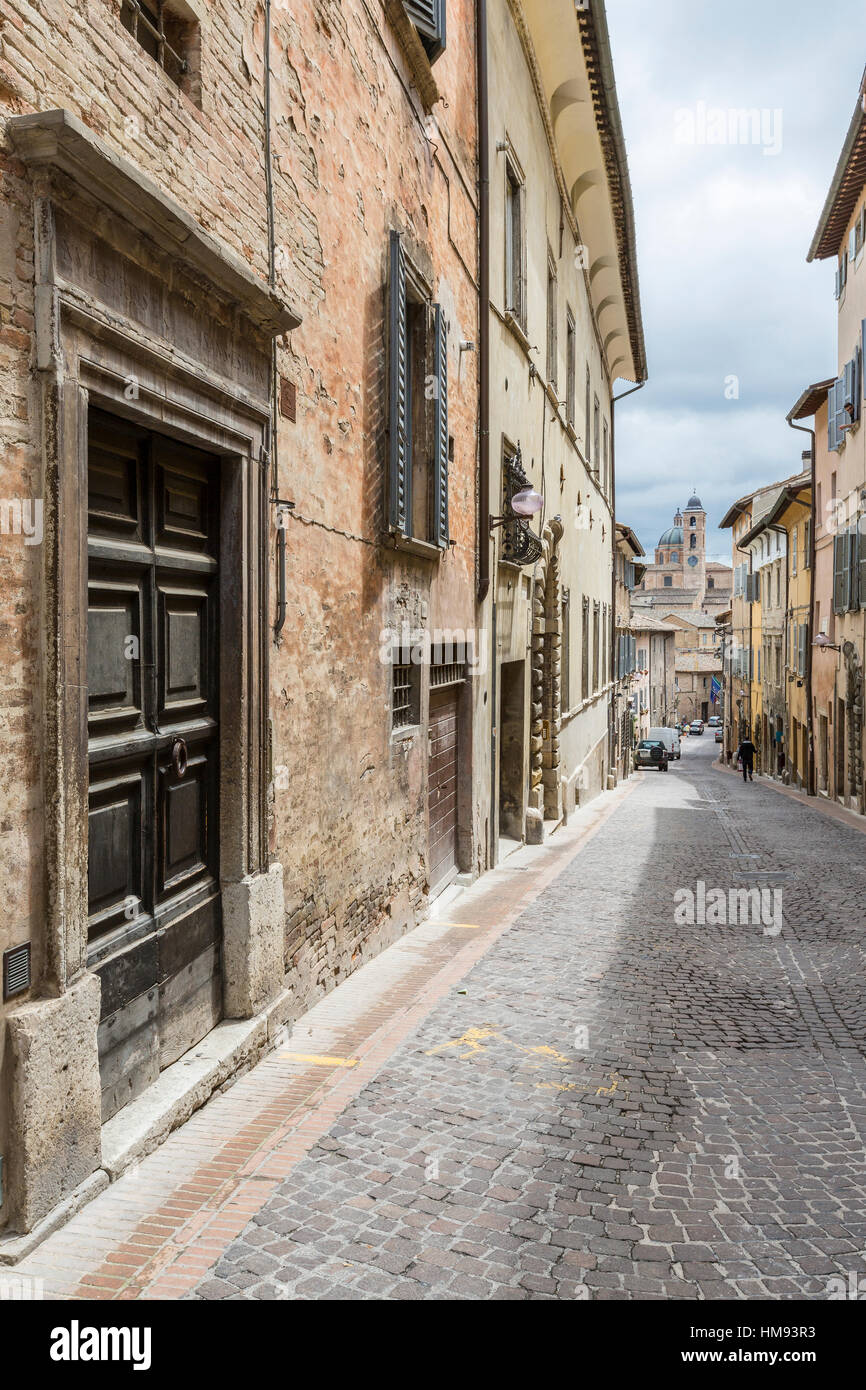 Une ruelle médiévale de la colline la ville avec la Piazza Duca Federico en arrière-plan, Urbino, Province de Pesaro, Marches, Italie Banque D'Images