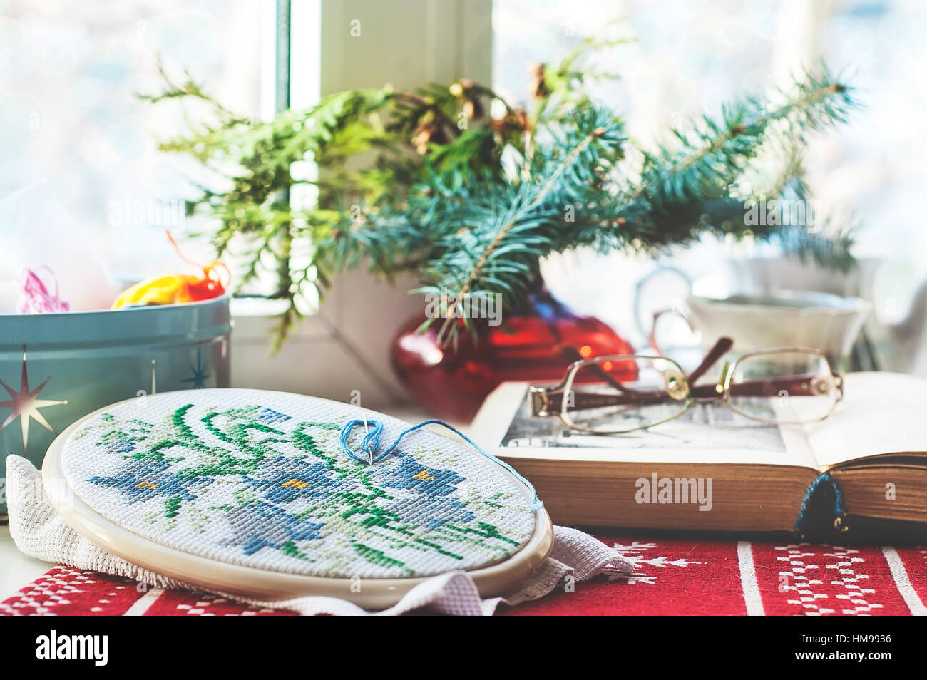 La vie encore d'hiver : hoop avec des fleurs brodées, livre ouvert, verres, théière et tasse, fils colorés dans la case et l'arbre de Noël dans un vase. Sélectionnez Banque D'Images