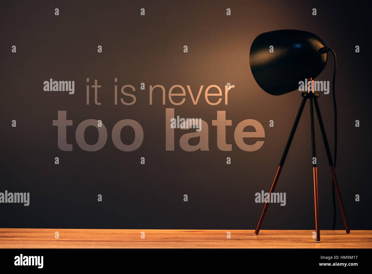 Il n'est jamais trop tard citation de motivation message sur le mur derrière le bureau bureau éclairé par l'ampoule Banque D'Images