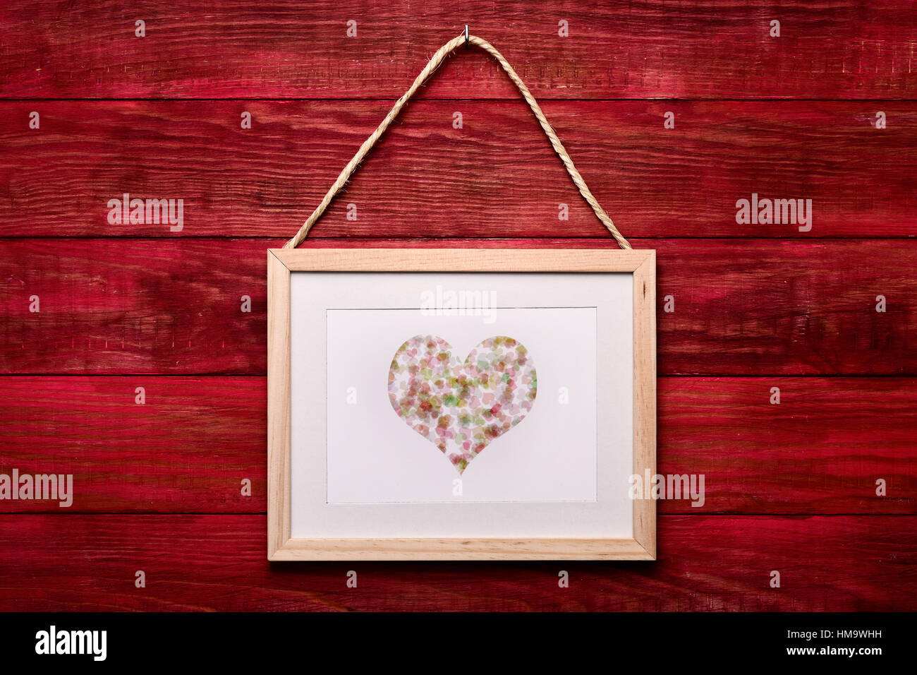 Une photo en bois avec un coeur, faite par moi-même, suspendu à un mur en bois rouge Banque D'Images