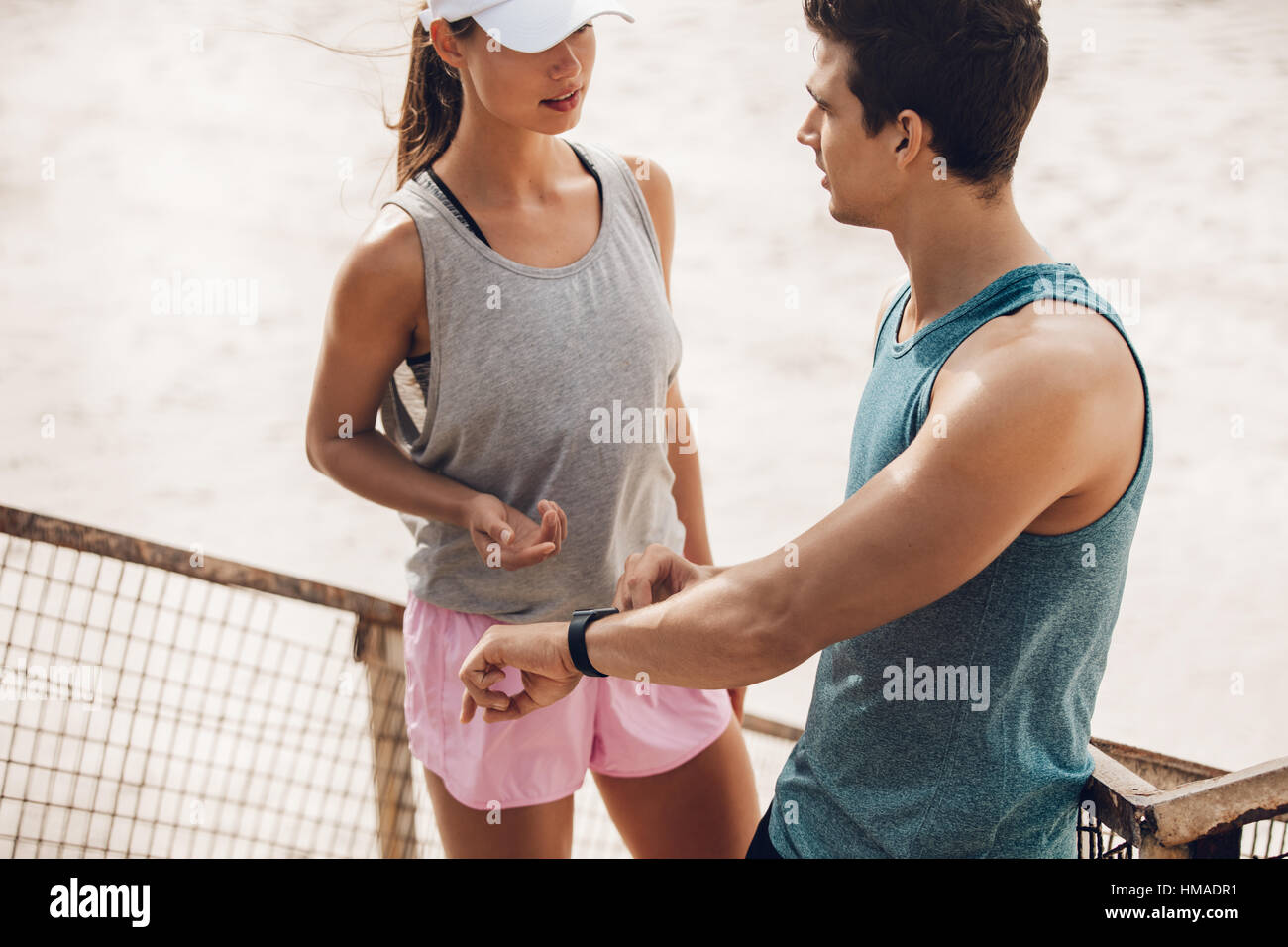 Jeune couple de discuter de l'entraînement pendant l'entraînement briser à l'extérieur. Porteur avec moniteur de fréquence cardiaque sur la plage. Banque D'Images