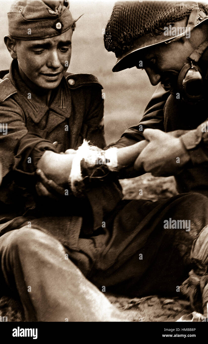 Ce 'Superman' Nazi semble être dans son "adolescence" et son expression n'est pas exactement celle de l'héros conquérant comme un soldat américain se penche sur l'entrecuisse du dommage en attendant l'arrivée d'un médecin. Le 6 septembre 1944. Waks. (Army Surgeon General) NARA DOSSIER #  : 112-SGA-44-14053 LIVRE Guerres et conflits #  : 1287 Banque D'Images