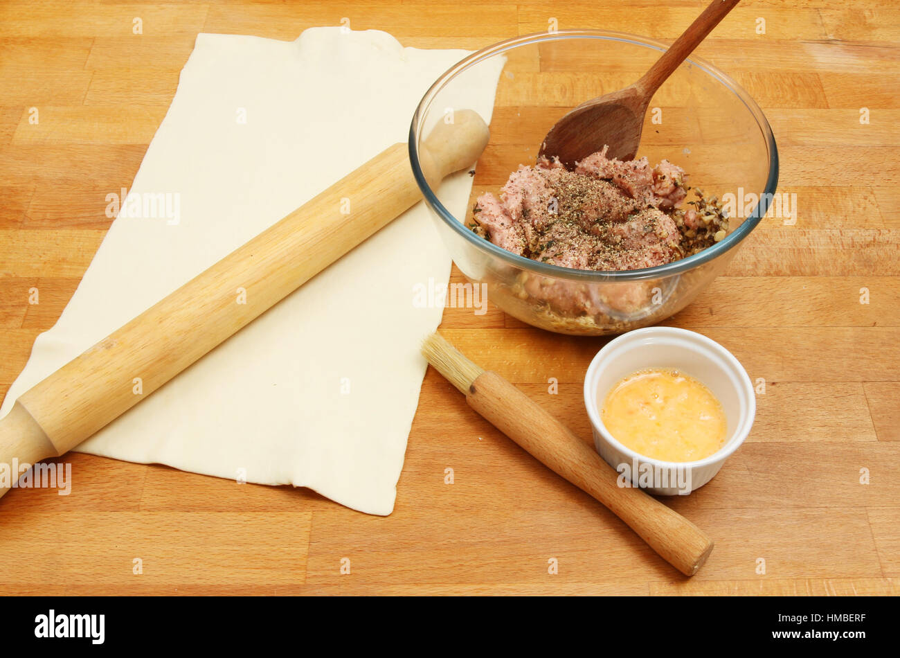 Ingrédients pour pâtisserie, pains à saucisse chair à saucisse, l'oeuf battu et sur un plan de travail de cuisine Banque D'Images