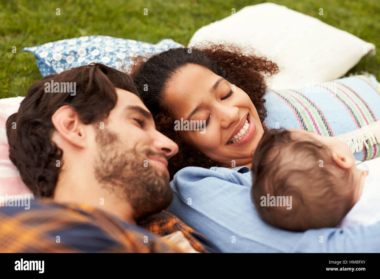 Famille avec bébé détente sur tapis en ensemble de jardin Banque D'Images