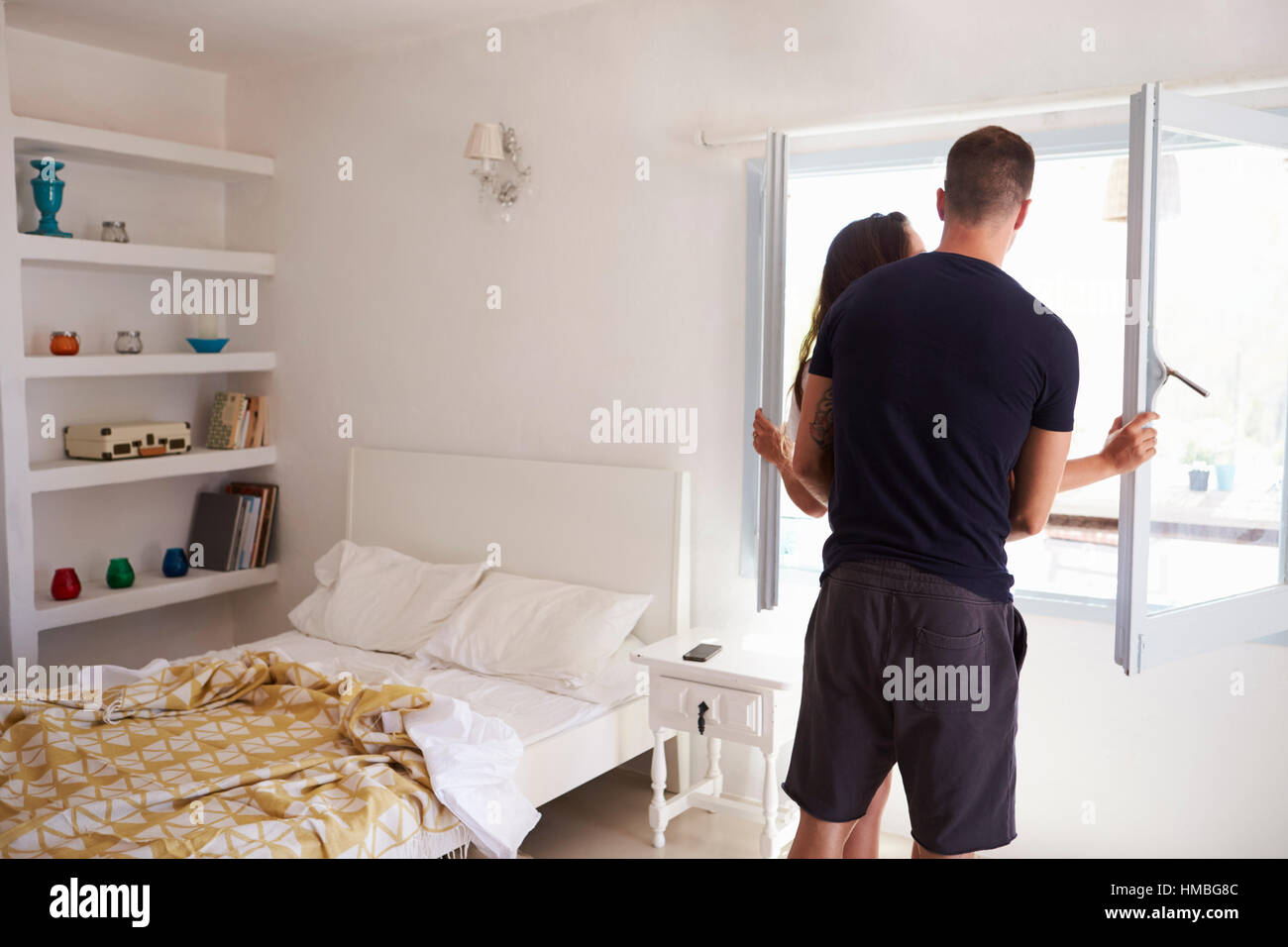 Couple par fenêtre dans une chambre, vue arrière trois quarts Banque D'Images