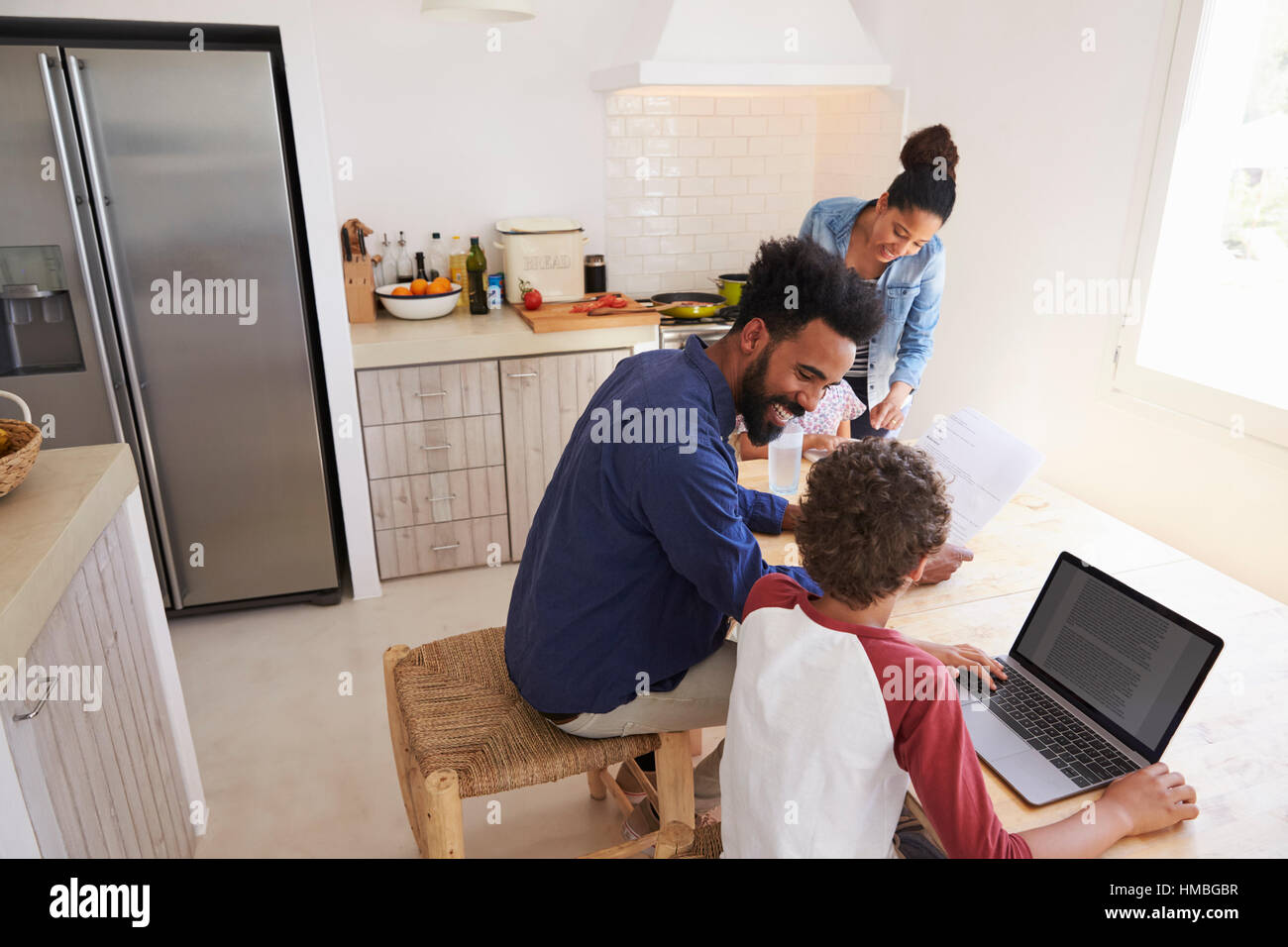 Les parents d'aider les enfants à faire leurs devoirs dans la cuisine, elevated view Banque D'Images