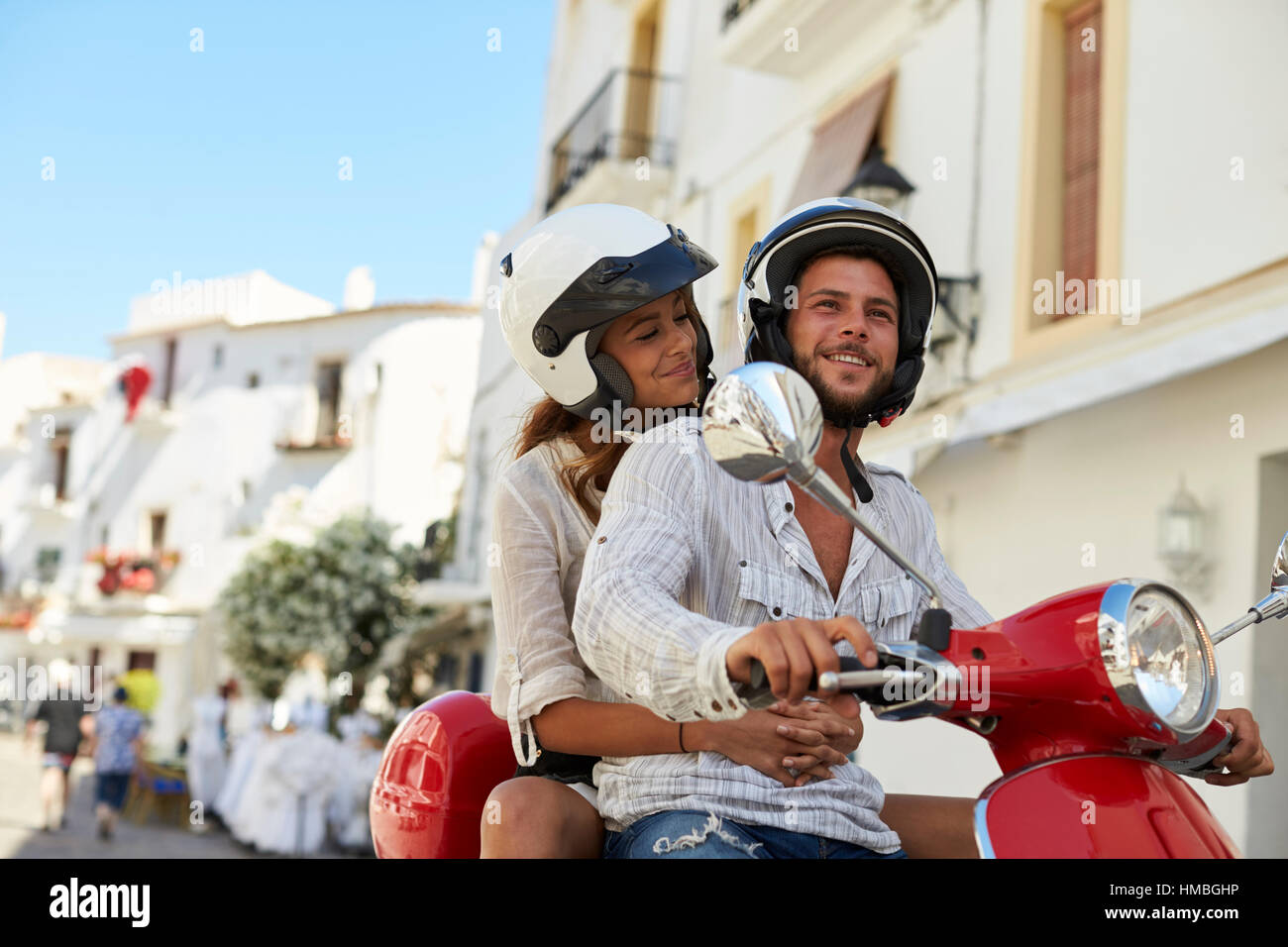 Young adult couple sur un scooter dans une rue, Ibiza Banque D'Images