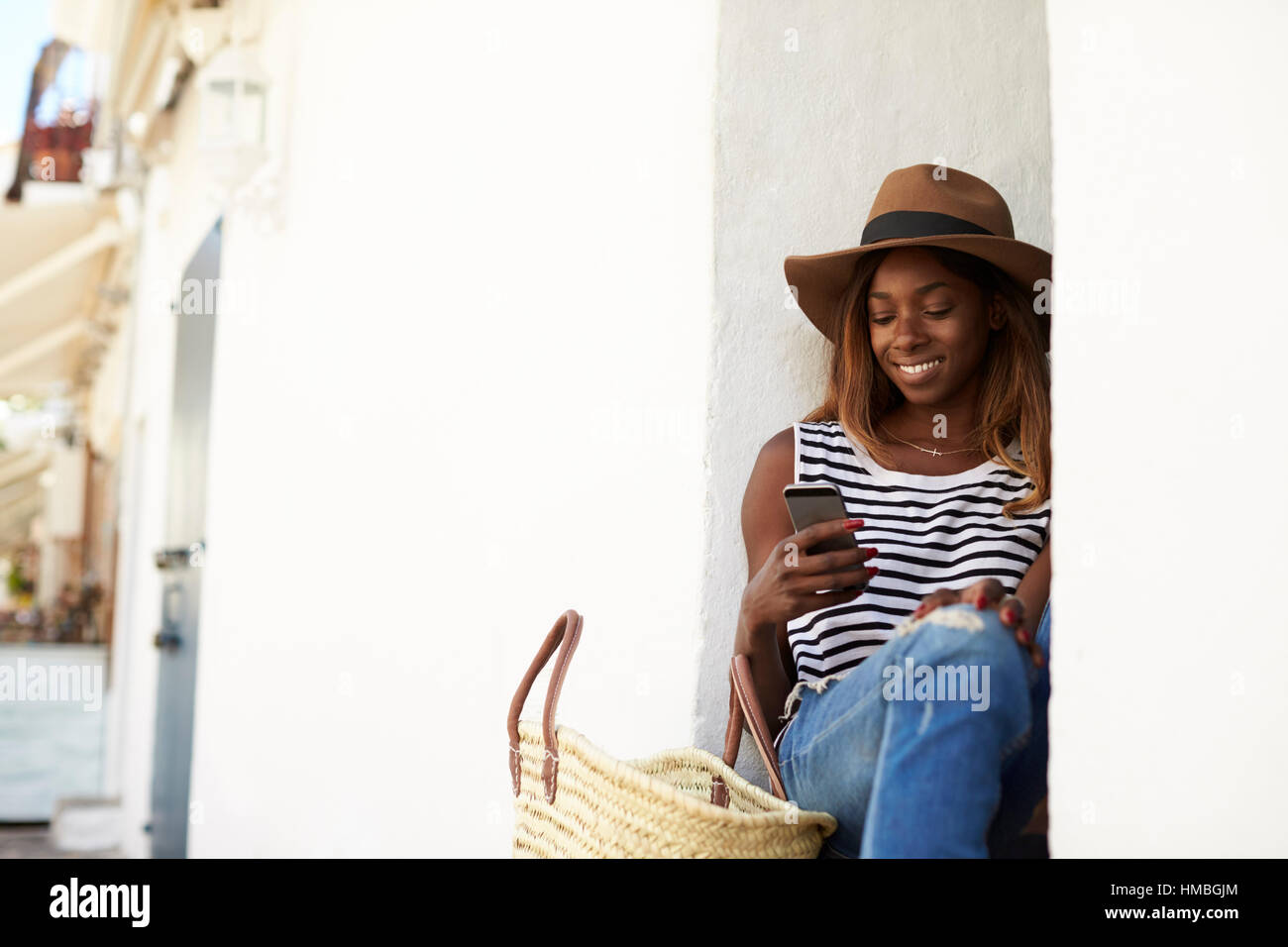 Jeune femme en vacances sitting on steps looking at phone Banque D'Images