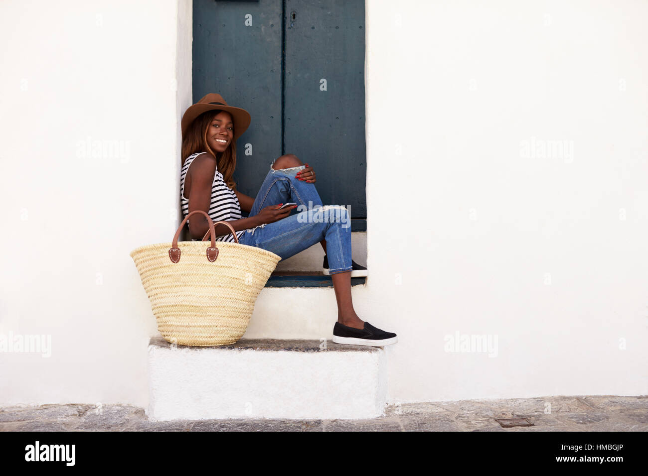 Jeune femme en vacances assis sur les marches, à la recherche d'appareil photo Banque D'Images