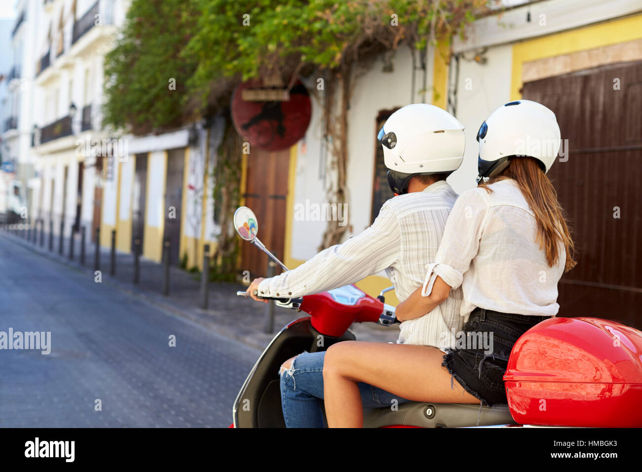 Young adult couple sur un scooter dans une rue, Ibiza Banque D'Images