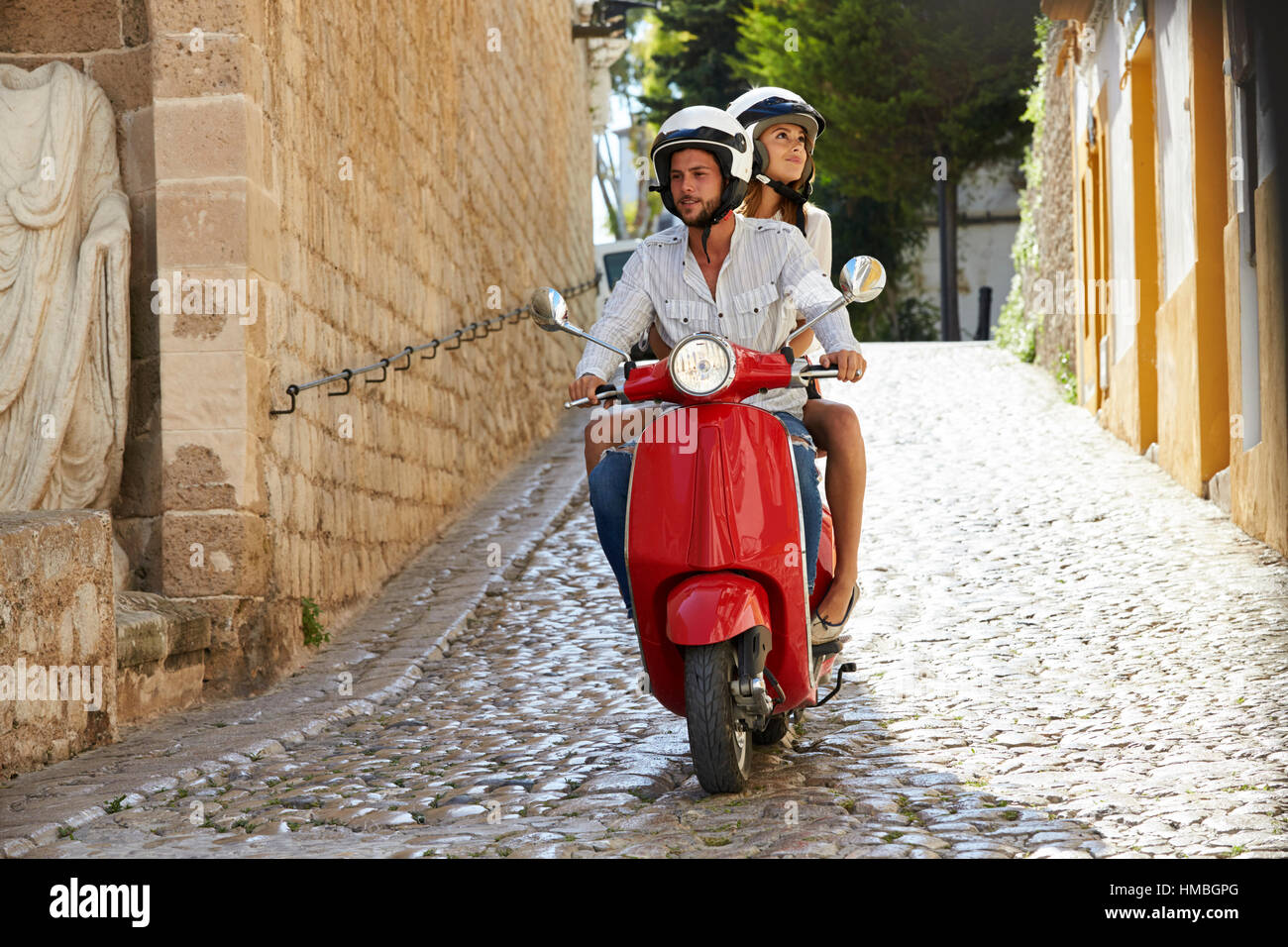Couple riding scooter dans la vieille rue d'Ibiza, pleine longueur Banque D'Images