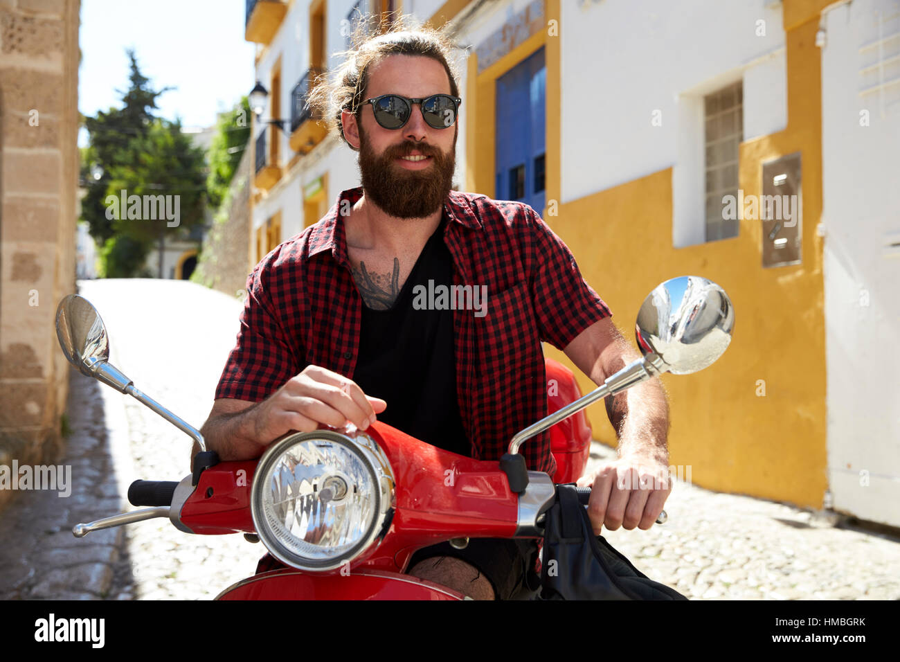 Jeune homme barbu assis sur scooter, Ibiza, Espagne Banque D'Images