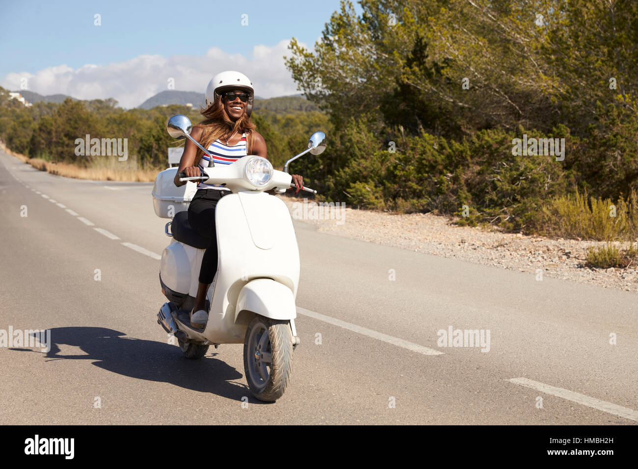 Young Woman Riding Scooter On Country Road Banque D'Images