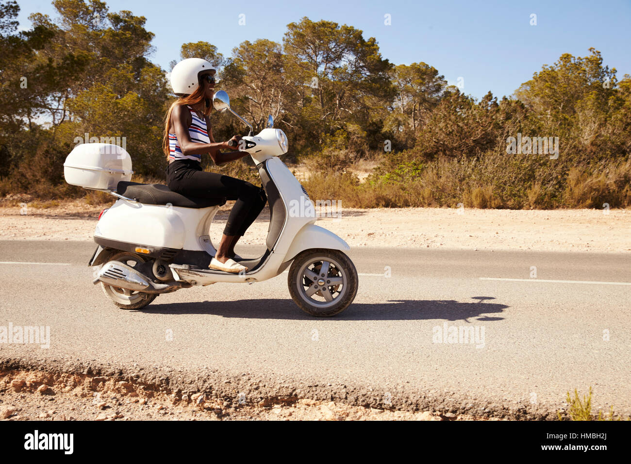 Young Woman Riding Scooter On Country Road Banque D'Images