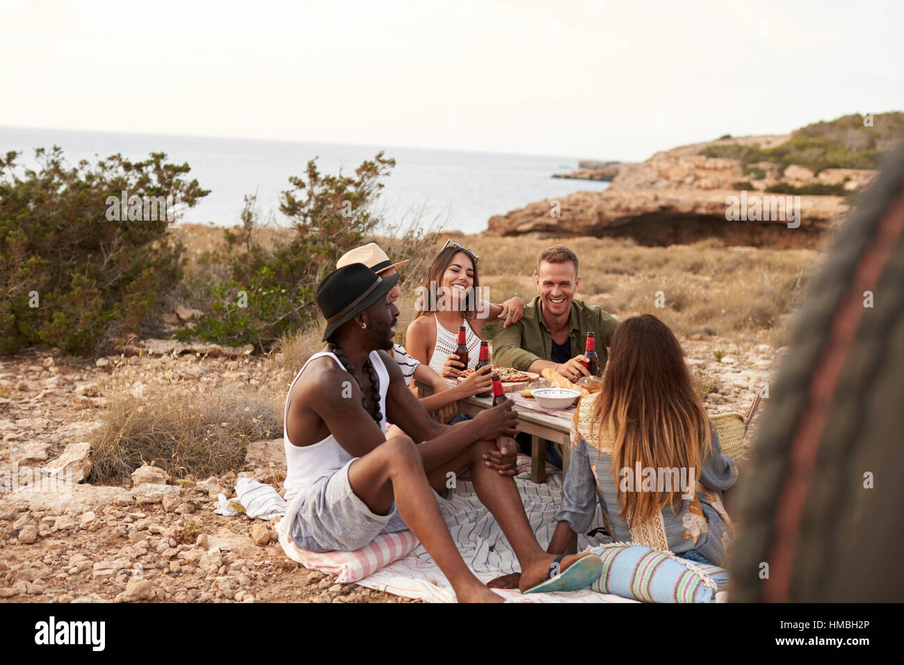 Groupe d'amis profitant de pique-nique sur la mer par des falaises Banque D'Images