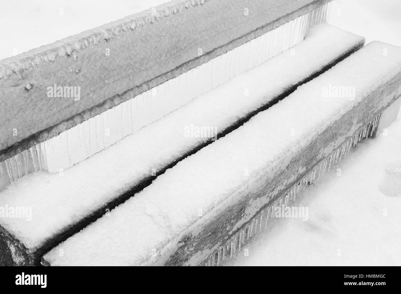 La pluie ou neige fondue couverts ce banc dans un parc Banque D'Images