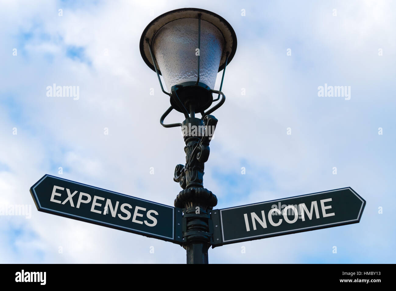 Éclairage public avec deux flèches opposées sur fond bleu nuageux. La notion de revenu par rapport aux dépenses. Banque D'Images