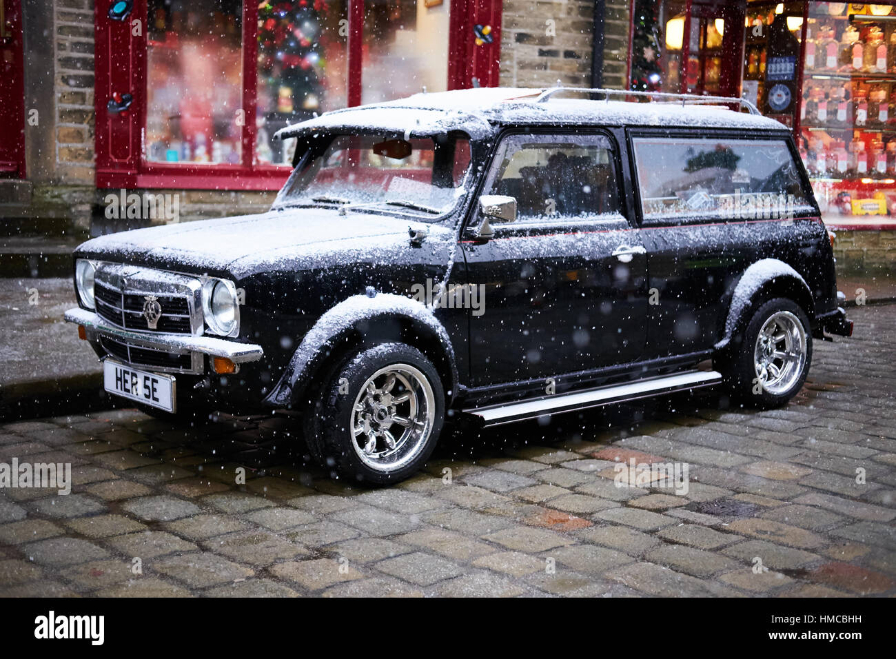 Un classique Mini Clubman Estate converti à l'air d'un corbillard dans une rue pavée dans la neige à un événement steampunk. Banque D'Images