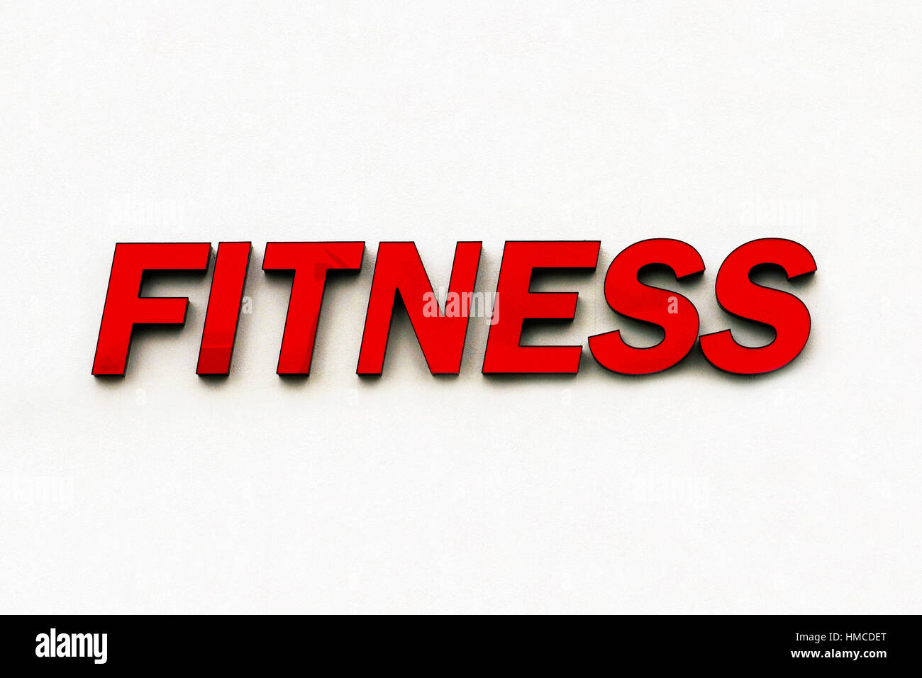 Plastique rouge signe du mot 'Fitness' annonce un gymnase et est isolé sur un mur blanc arrière-plan. Banque D'Images