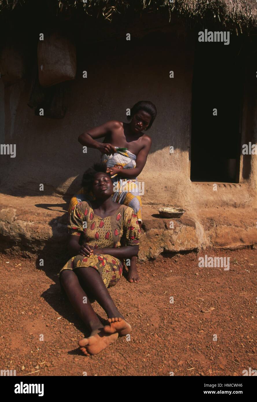 Une jeune femme se peigner les cheveux d'une autre femme, Biankouma, Côte d'Ivoire. Banque D'Images
