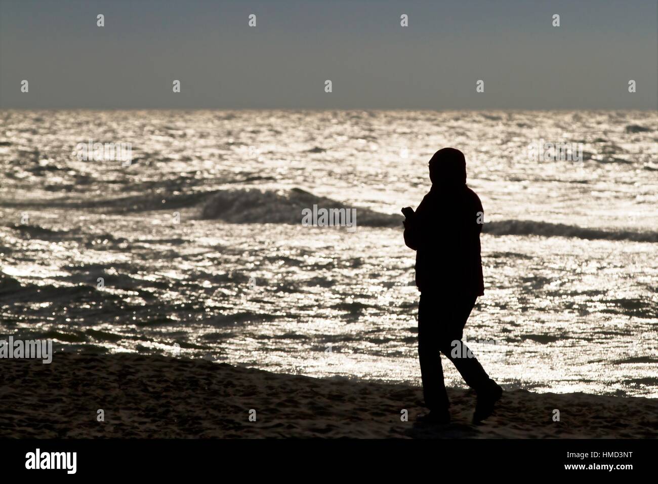 Silhouette de femme (avec téléphone) sur la plage Banque D'Images