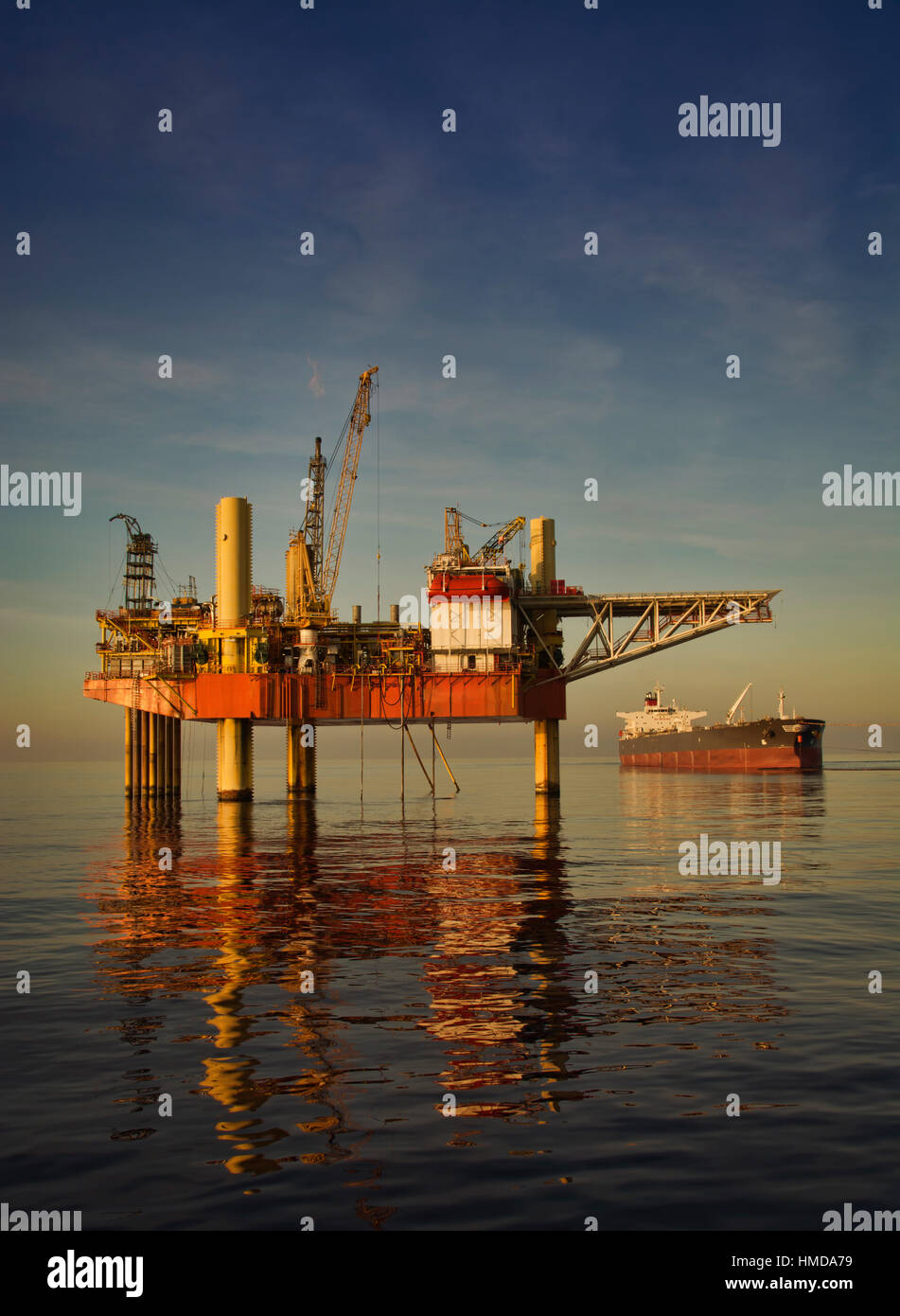 Cric l'Oil Rig et pétroliers en mer au coucher de soleil avec une mer calme et un ciel clair Banque D'Images